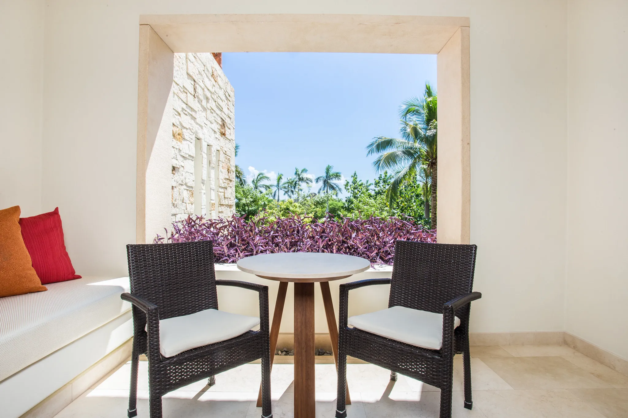 Junior Suite furnished terrace with table and chairs at Secrets Akumal Riviera Maya overlooking tropical greenery.